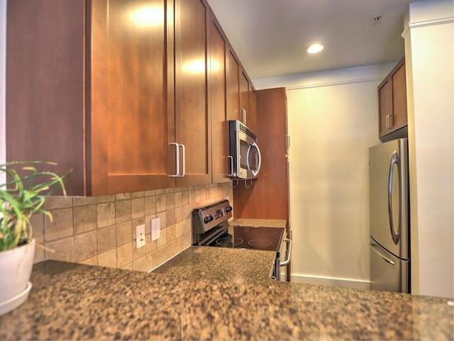 kitchen with decorative backsplash, stainless steel appliances, and dark stone countertops