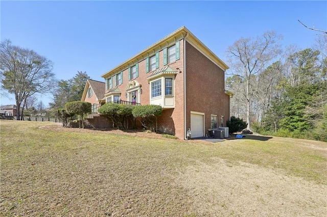 view of side of home featuring a garage, cooling unit, brick siding, and a yard