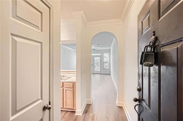 hall with light hardwood / wood-style floors and ornamental molding