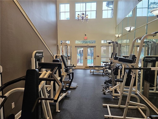 exercise room featuring french doors, a notable chandelier, and a high ceiling