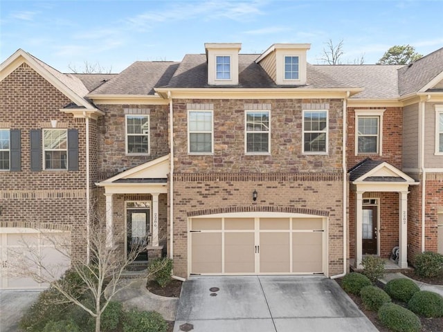 view of property with stone siding, roof with shingles, concrete driveway, an attached garage, and brick siding