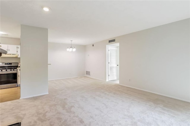 unfurnished living room with light colored carpet and an inviting chandelier