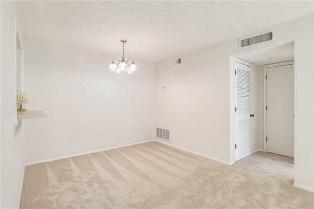 carpeted spare room with an inviting chandelier