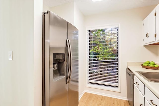 kitchen with stainless steel appliances, sink, light hardwood / wood-style floors, and white cabinets