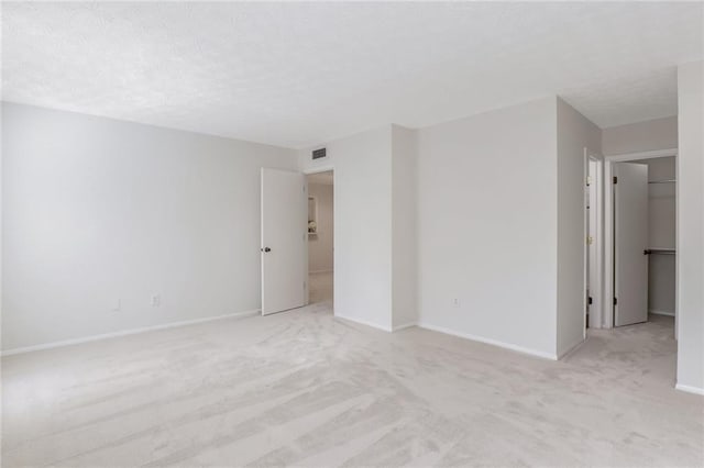 empty room with light colored carpet and a textured ceiling