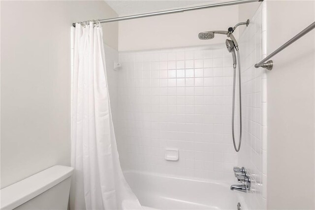 bathroom with shower / bath combination with curtain and toilet