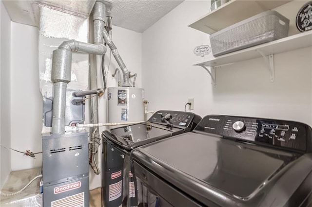 clothes washing area featuring washing machine and clothes dryer, water heater, and a textured ceiling