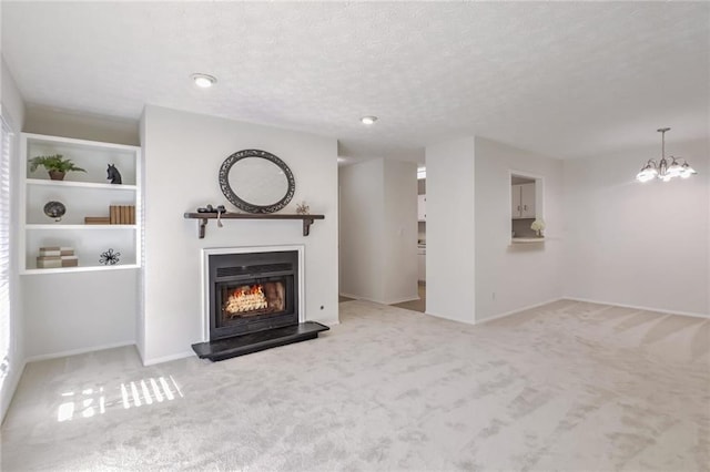 unfurnished living room featuring a chandelier, light colored carpet, a textured ceiling, and built in shelves