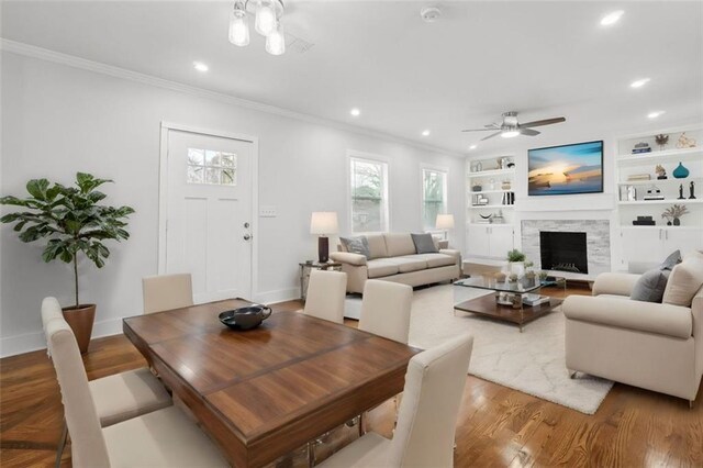 dining room featuring built in features, a fireplace, ceiling fan, and ornamental molding