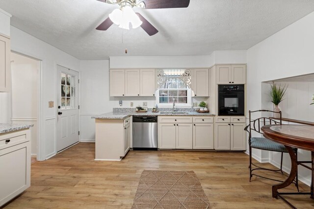 kitchen with sink, light hardwood / wood-style flooring, black electric cooktop, dishwasher, and cream cabinetry