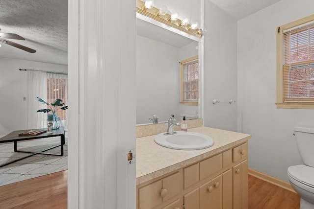 bathroom featuring toilet, a textured ceiling, vanity, hardwood / wood-style flooring, and ceiling fan