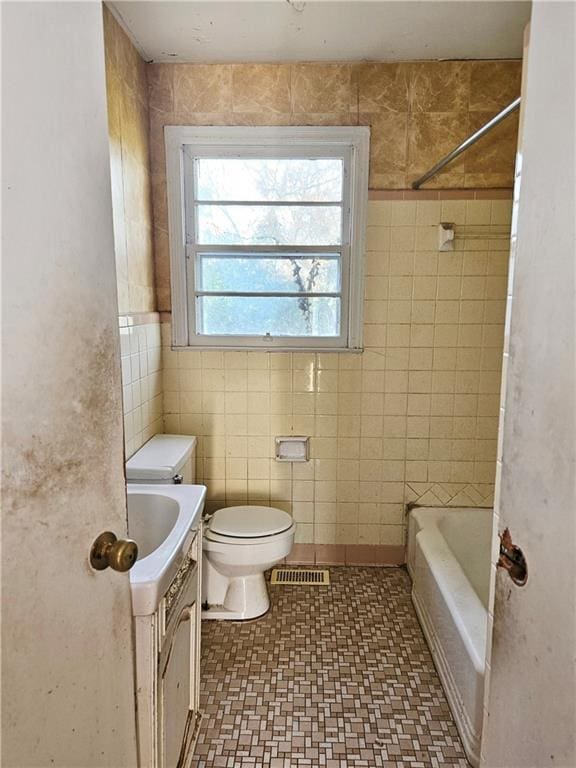 full bath featuring visible vents, vanity, toilet, and tile walls