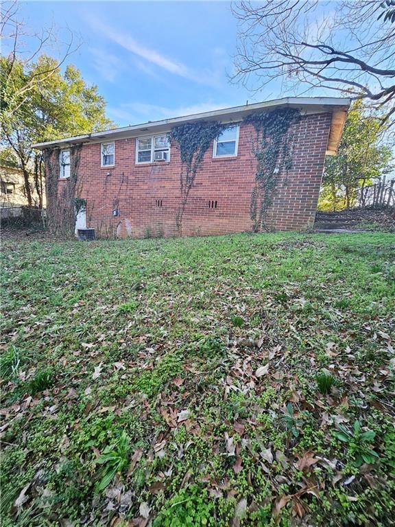 view of home's exterior featuring crawl space, a yard, fence, and brick siding