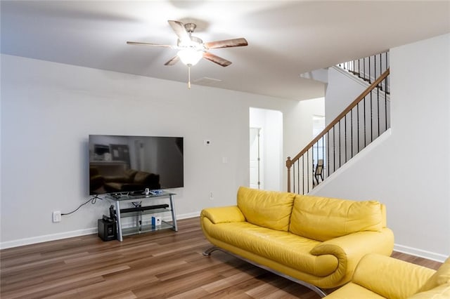 living room featuring baseboards, stairway, ceiling fan, and wood finished floors