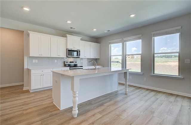 kitchen featuring light countertops, visible vents, backsplash, appliances with stainless steel finishes, and a sink