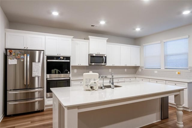 kitchen with dark wood-type flooring, visible vents, white cabinets, appliances with stainless steel finishes, and decorative backsplash