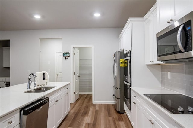 kitchen featuring stainless steel appliances, wood finished floors, a sink, light countertops, and tasteful backsplash