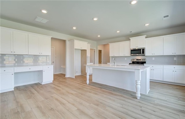 kitchen featuring visible vents, decorative backsplash, stainless steel appliances, light wood-style floors, and white cabinetry