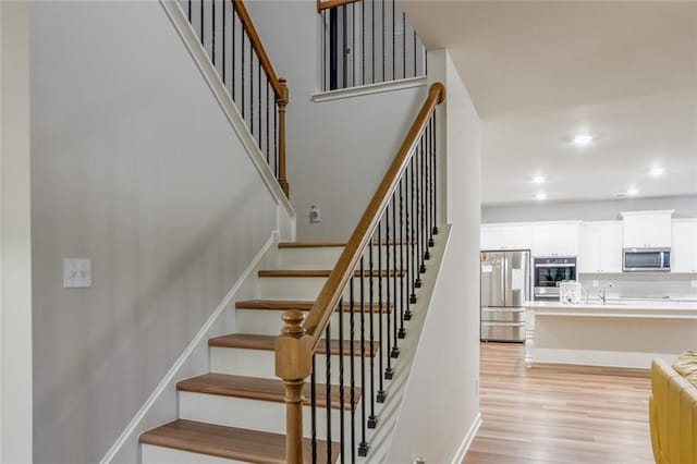 stairway featuring recessed lighting, wood finished floors, and baseboards