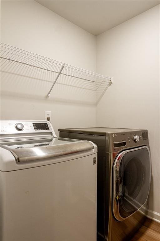 laundry room featuring laundry area, washer and clothes dryer, baseboards, and wood finished floors