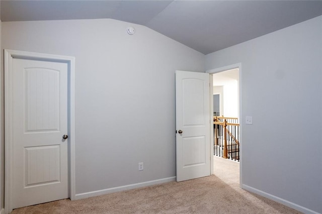 unfurnished bedroom with carpet floors, lofted ceiling, and baseboards