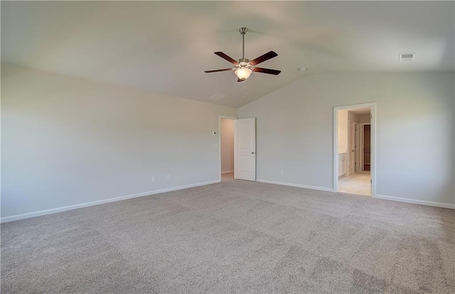 spare room featuring light colored carpet, visible vents, a ceiling fan, vaulted ceiling, and baseboards