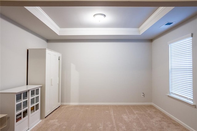 unfurnished room with ornamental molding, a tray ceiling, carpet flooring, and baseboards