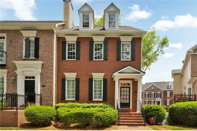 colonial inspired home featuring brick siding and a chimney