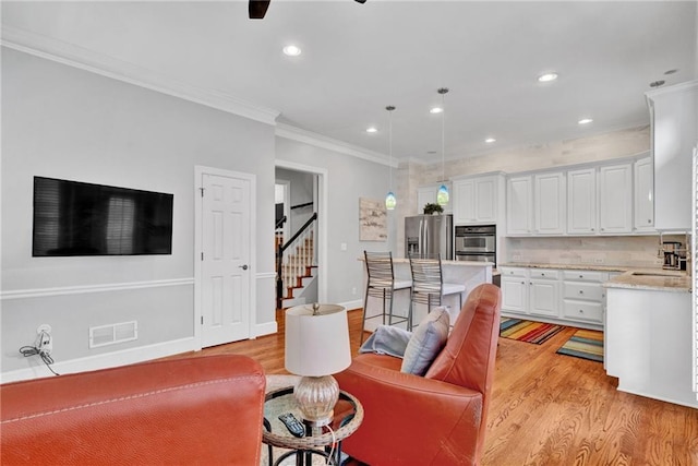 living room featuring light wood finished floors, crown molding, recessed lighting, stairway, and ceiling fan