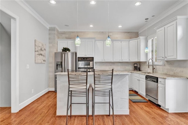 kitchen with appliances with stainless steel finishes, white cabinetry, a kitchen island, crown molding, and recessed lighting
