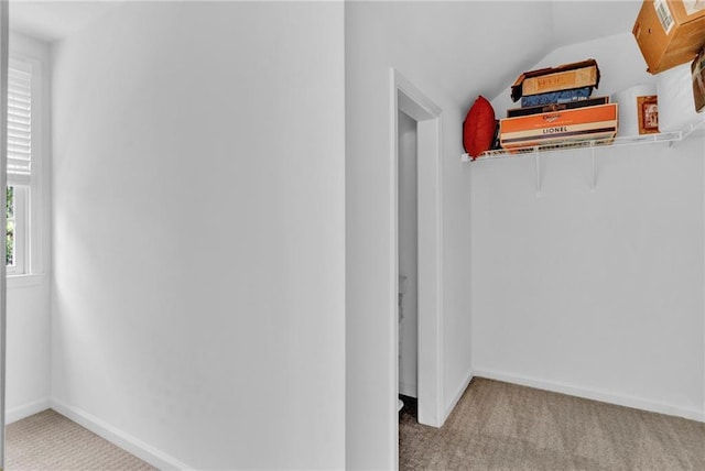 interior space featuring carpet floors, vaulted ceiling, and baseboards
