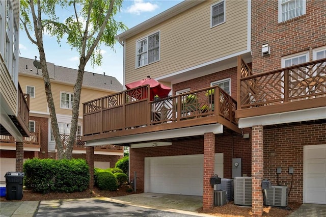 back of property with a garage, brick siding, central AC unit, and driveway