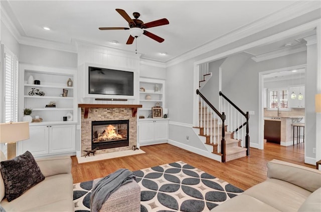 living room with light wood-style floors, crown molding, ceiling fan, stairs, and a multi sided fireplace