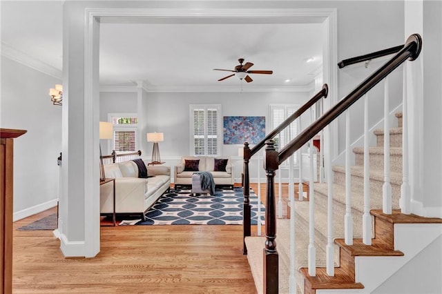 living area featuring ceiling fan, ornamental molding, light wood finished floors, stairs, and baseboards