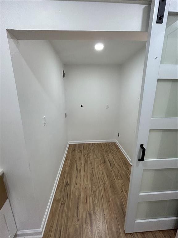 clothes washing area featuring built in shelves, baseboards, and wood finished floors