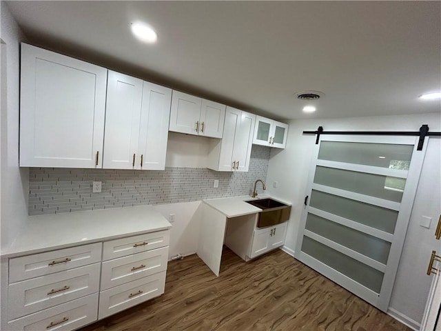 kitchen featuring visible vents, dark wood-style flooring, a sink, white cabinets, and a barn door