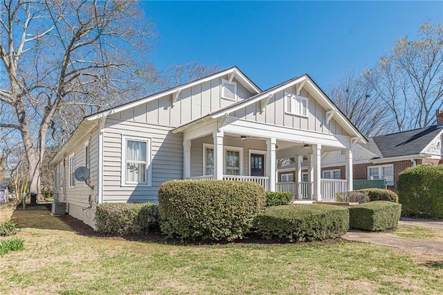 view of front of property featuring covered porch, board and batten siding, a front yard, and a ceiling fan