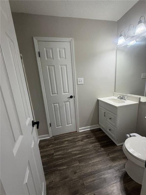 bathroom with vanity, toilet, hardwood / wood-style floors, and a textured ceiling