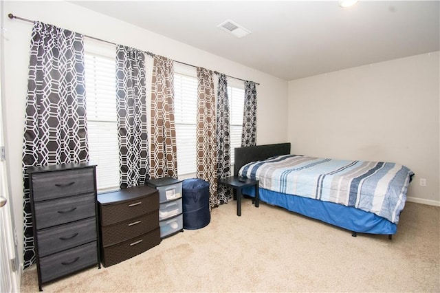 bedroom featuring light colored carpet and multiple windows