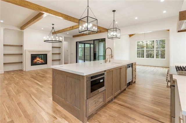 kitchen featuring beam ceiling, sink, pendant lighting, a spacious island, and light wood-type flooring