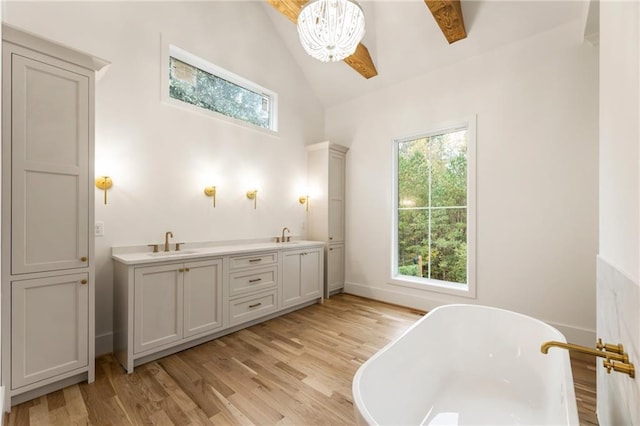 bathroom with hardwood / wood-style floors, vanity, vaulted ceiling, and a washtub