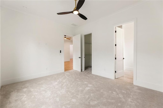 unfurnished bedroom featuring light colored carpet, a spacious closet, and ceiling fan