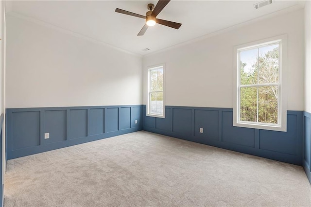 empty room featuring ceiling fan, light colored carpet, and ornamental molding