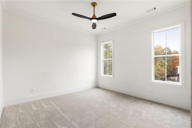 carpeted spare room featuring plenty of natural light, ceiling fan, and ornamental molding