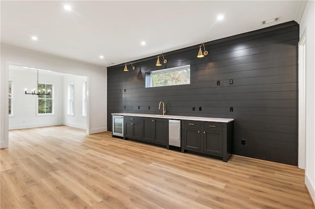 bar featuring sink, light hardwood / wood-style floors, beverage cooler, and wood walls