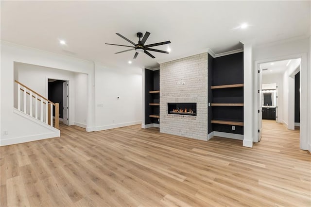 unfurnished living room featuring built in shelves, ceiling fan, light hardwood / wood-style flooring, and a fireplace