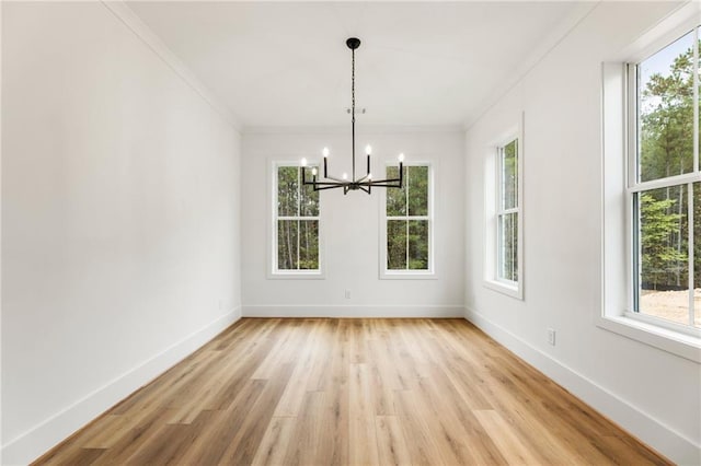 unfurnished dining area with crown molding, light hardwood / wood-style floors, and an inviting chandelier