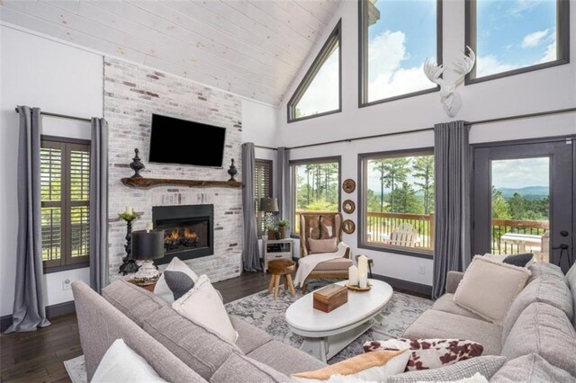 living room with high vaulted ceiling, a large fireplace, a wealth of natural light, and dark hardwood / wood-style floors