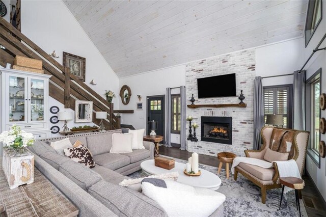 living room featuring hardwood / wood-style flooring, plenty of natural light, high vaulted ceiling, and a brick fireplace