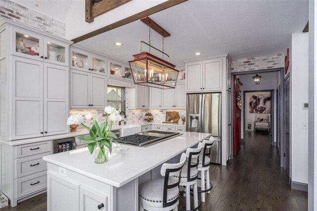 kitchen featuring white cabinets, a kitchen island, appliances with stainless steel finishes, a kitchen bar, and dark hardwood / wood-style flooring